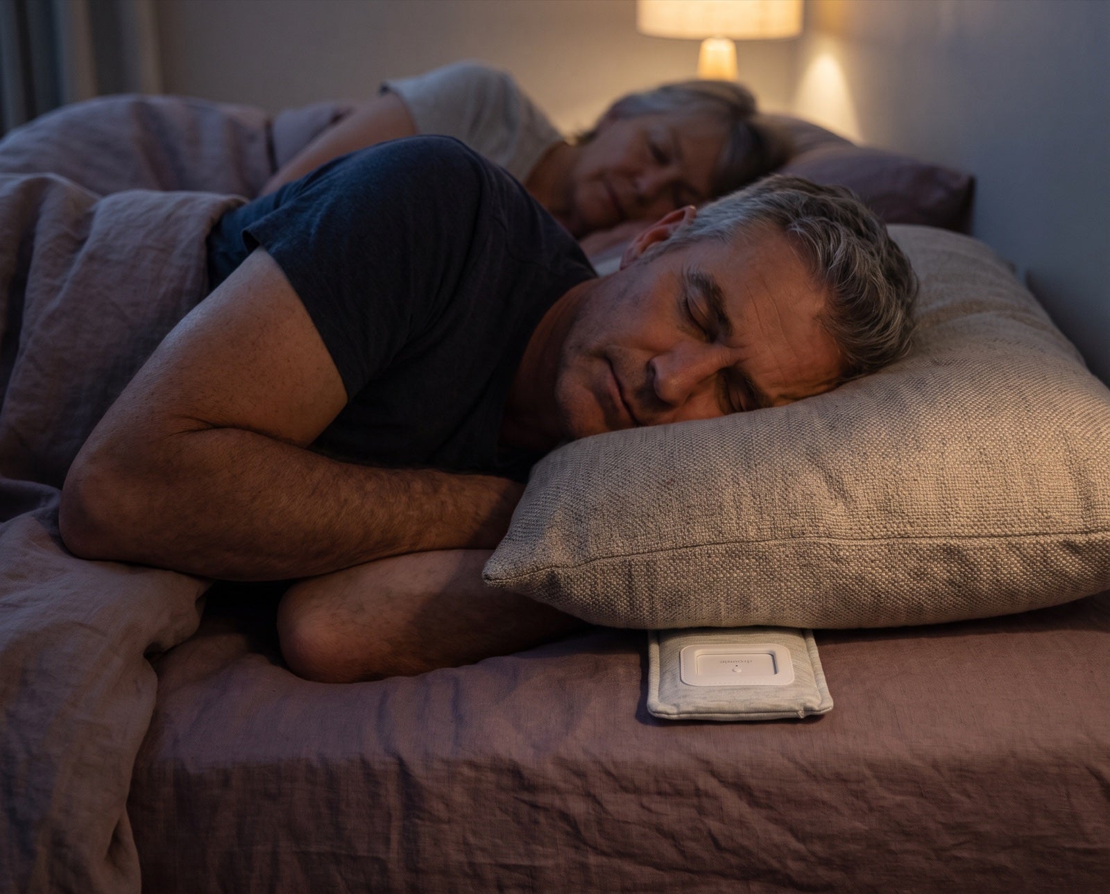 A couple asleep in one bed, the Drowsie speaker under the near pillow